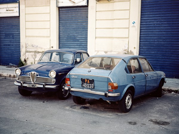 Stehen in Palermo einfach auf der Straße: Links eine Alfa Romeo Giulietta Berlina der dritten Serie aus den Baujahren 1961-1964, rechts ein Alfasud der ersten Serie aus den Baujahren 1972 bis 1980. Technisch waren beide Modelle sehr fortschrittlich, die Giulietta auch ein Verkaufsschlager. Minderwertige Metalle, fehlende Rostvorsorge und schlechte Verarbeitung des Alfasuds begründete hingegen den schlechten Ruf Alfa Romeos seit den Siebzigern über Jahrzehnte hinweg. Gebaut wurde er im süditalienischen (deshalb Alfasud) Werk Pomigliano d’Arco, welches in den zwölf Produktionsjahren 700mal von den zum großen Teil ungelernten Arbeitern bestreikt wurde.