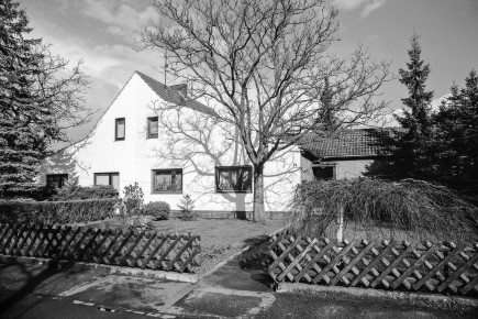 Häufig anzutreffende asymmetrische Erweiterung des Haustyps P.Beide Eingangsbereiche der Haushälften wurden überbaut, rechts wurde außerdem die Raumhöhe des Anbaus vergrößert und ein traufständiger Riegel parallel zur Straße hinzugefügt.