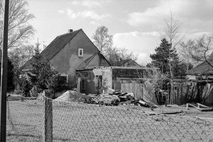 Auf Restparzellen -ungünstig gelegenen Eckgrundstücken, die zu wenig Raum für ein Doppelhaus boten- wurden Einfamilienhäuser vom Typ P1 gebaut, hier die Rückansicht des Hauses An den Birken 1h.
Der rückwärtige und bereits erweiterte Stallanbau wird abgerissen. Die Wände der Erweiterung bestehen aus den unterschiedlichsten Baumaterialien: helle Klinker, dunkle Klinker, großvolumige Gasbetonsteine.
Geld war in der Siedlung nicht viel vorhanden, dafür aber handwerkliches Geschick und Organisationstalent. Man nahm an Baustoffen, was man kriegen konnte und nach Feierabend wurde der Anbau in Eigenregie hochgezogen.